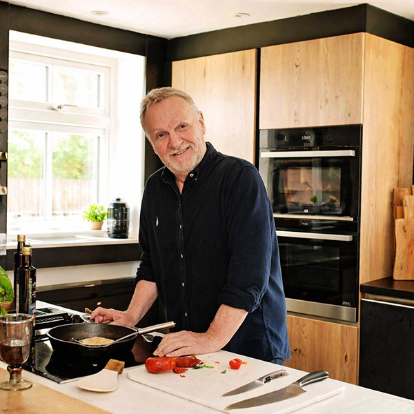 Man in his 60s black shirt stood at a Corian resin kitchen worktop